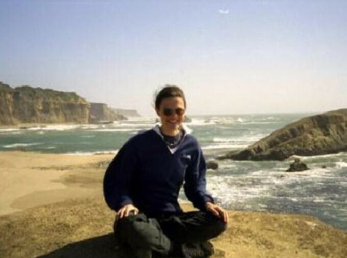 Photograph of Professor Katriona Shea sitting on the beach