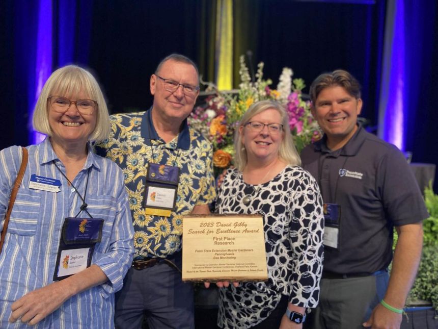 four people pose with an award plack